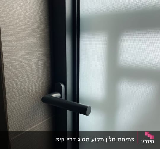 ידית חלון שחורה על רקע זכוכית חלבית